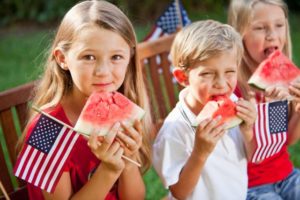 children eating watermelon & holding American flags