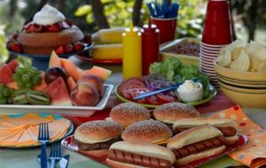 grilled burgers, hot dogs, and condiments on table