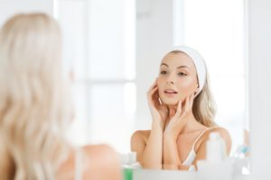 Woman with healthy skin looking in mirror