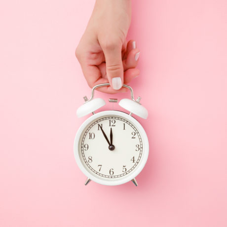 alarm clock sleep with hand on pink background